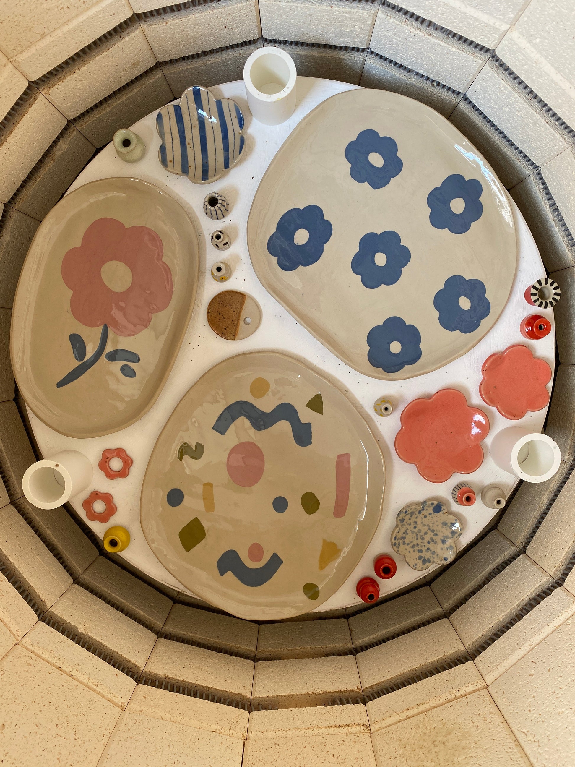 Collection of ceramic plates with various patterns inside a kiln.